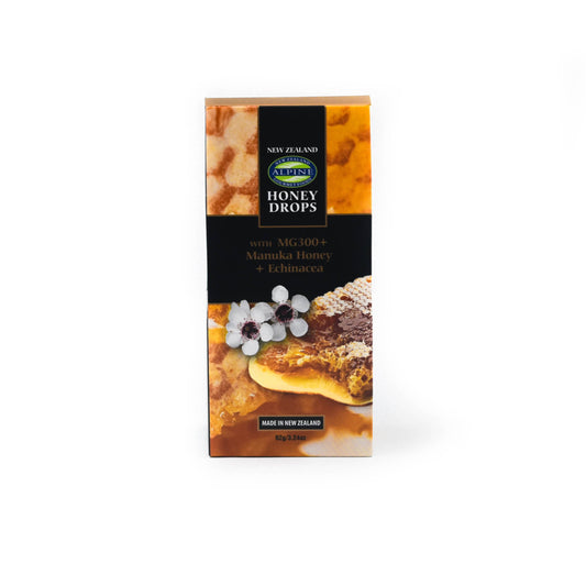 Pouch of Manuka Honey drops on a white background. 
The pouch is Orange with the honeycomb image and some manuka flowers. Middle is black with some text and top centre is the blue and green oval logo of alpine gourmet. 