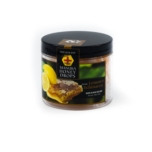 Tub of Manuka Honey Lemon drops on a white background. Tub has black lid and image of lemons & Manuka on it. 