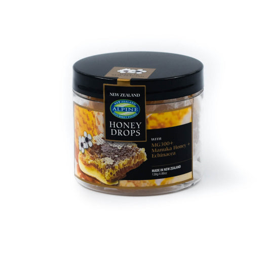 A clear jar with black lid containing individually wrapped Active 10+ Manuka Honey Drops with Echinacea. The label indicates that the product is made in New Zealand and has an image of manuka flowers and honeycomb 